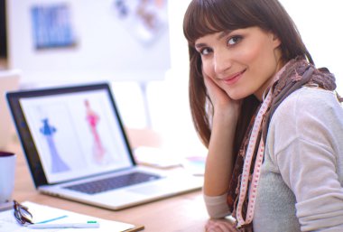 Ofis masasında oturan çekici kadın moda tasarımcısının portresi.