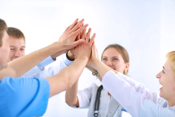 Doktorlar ve hemşireler tıbbi bir ekipte el ele tutuşuyorlar. 