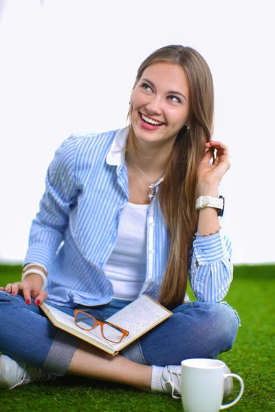 Young woman sitting with book on grass — Stock Photo, Image