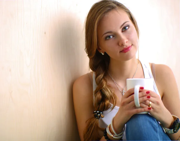 Beautiful woman sitting on the floor and holding a cup — Stock Photo, Image