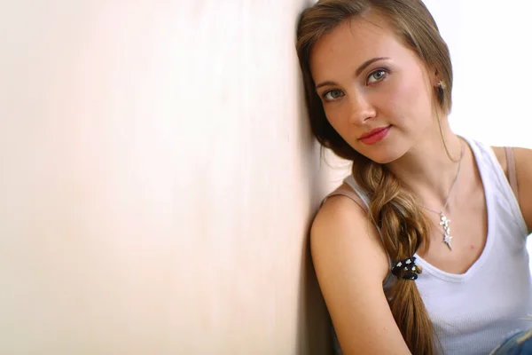 Młoda kobieta siedzi na podłodze w pobliżu ściany — Zdjęcie stockowe