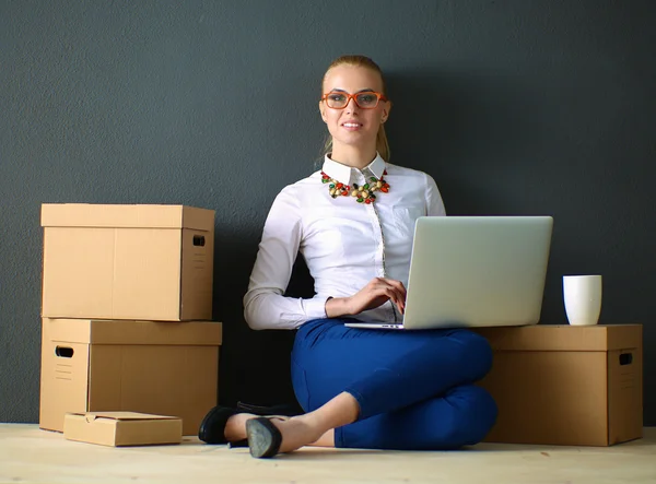 Žena sedící na podlaze u krabic s laptopem — Stock fotografie