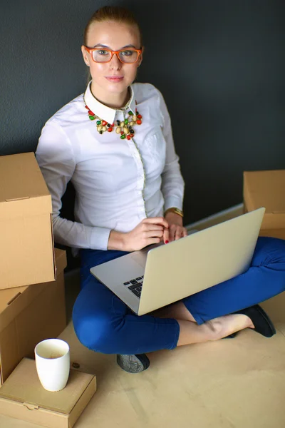 Vrouw zitten op de vloer in de buurt van een dozen met laptop — Stockfoto