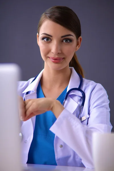 Médico feminino trabalhando sentado em fundo cinza — Fotografia de Stock