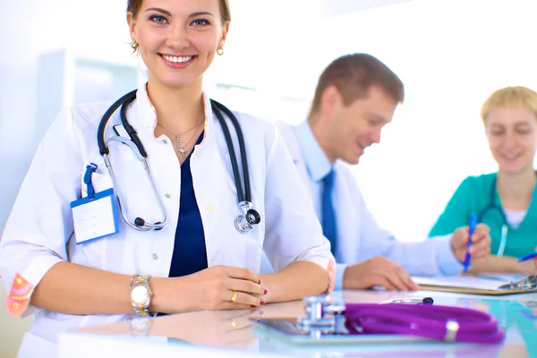 Vacker ung leende kvinnlig läkare sitter vid skrivbordet — Stockfoto