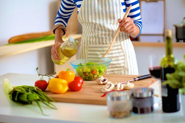 Jonge vrouw mengt verse salade — Stockfoto