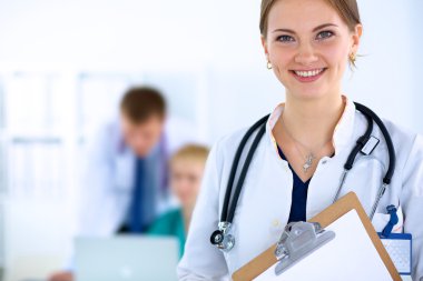 Tıbbî grubun önünde dosyası olan çekici bir kadın doktor.