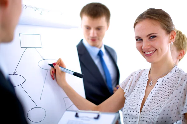 Businesswoman writing on flipchart while giving presentation to colleagues in office — Stock Photo, Image