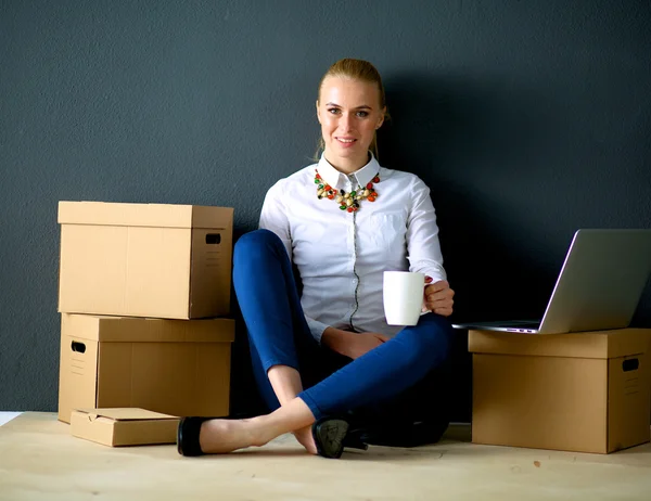 Mujer sentada en el suelo cerca de una caja con portátil —  Fotos de Stock