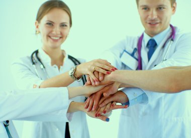 Doktorlar ve hemşireler tıbbi bir ekipte el ele tutuşuyorlar. 