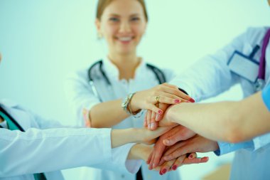 Doktorlar ve hemşireler tıbbi bir ekipte el ele tutuşuyorlar. 