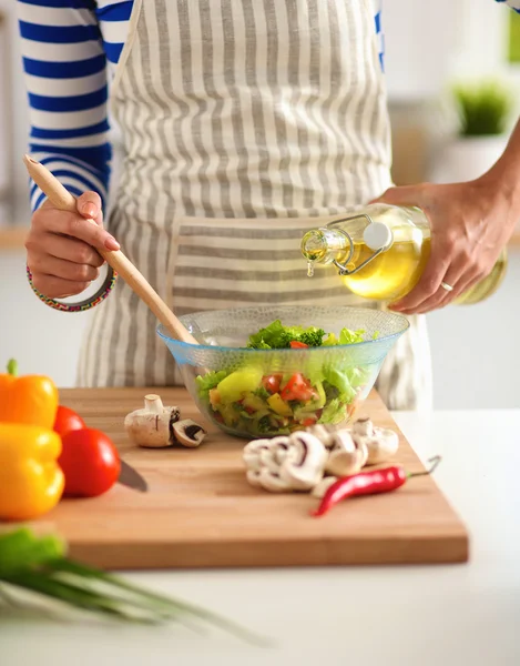 Jonge vrouw mengt verse salade — Stockfoto