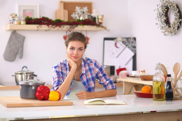 Glimlachende jonge vrouw in de keuken, geïsoleerd op kerst achtergrond — Stockfoto