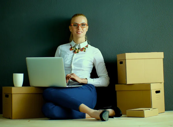 Mujer sentada en el suelo cerca de una caja con portátil —  Fotos de Stock