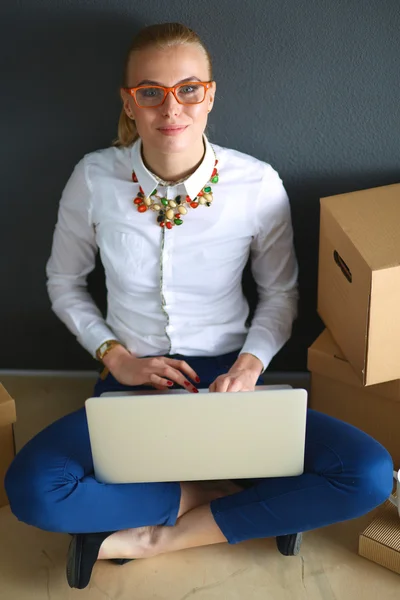 Femme assise sur le sol près d'une boîte avec ordinateur portable — Photo