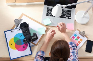 Masada dizüstü bilgisayarla oturan kadın fotoğrafçı.