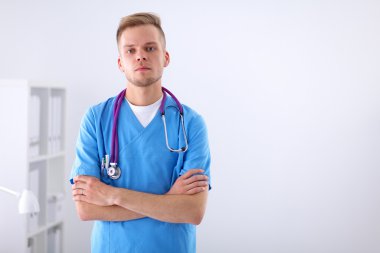 Steteskoplu doktor ayakta, çapraz kollu, beyaz arka planda izole.