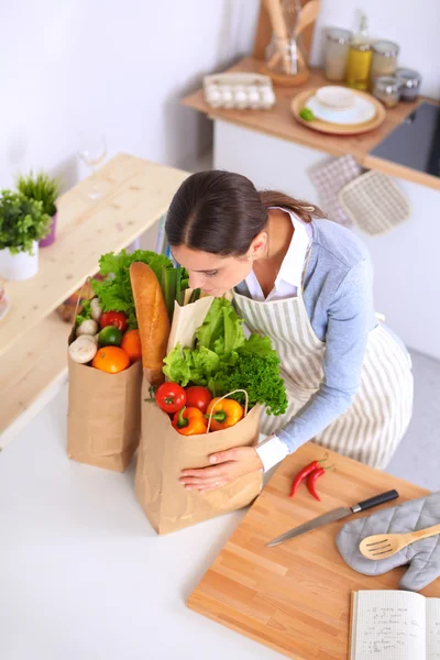 Mujer con bolsas de compras en la cocina en casa, de pie cerca del escritorio — Foto de Stock