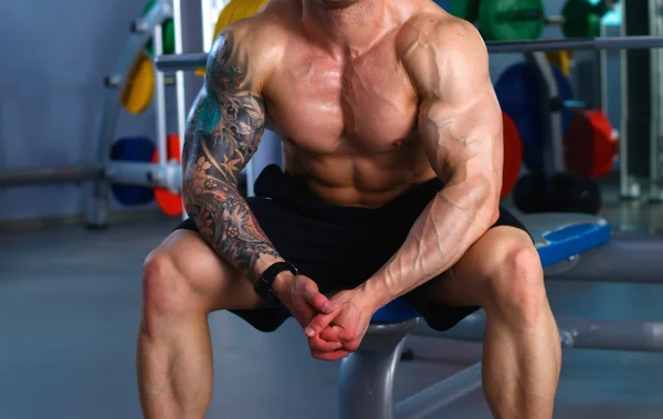 Junger schöner Mann sitzt nach dem Training im Fitnessstudio — Stockfoto