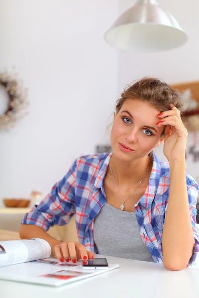 Mujer joven leyendo mgazine En la cocina en casa — Foto de Stock