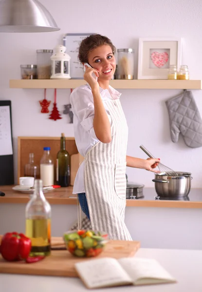 Portret van een lachende vrouw met telefoon in de keuken thuis — Stockfoto