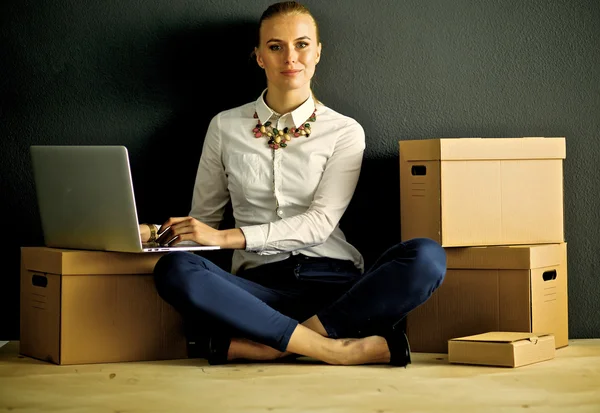 Femme assise sur le sol près d'une boîte avec ordinateur portable — Photo