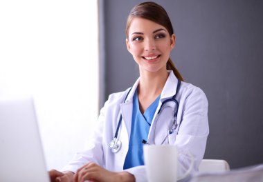 Gri arka planda oturan kadın doktor