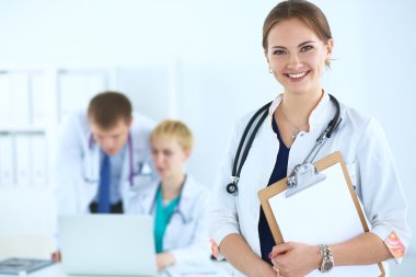 Tıbbî grubun önünde dosyası olan çekici bir kadın doktor.