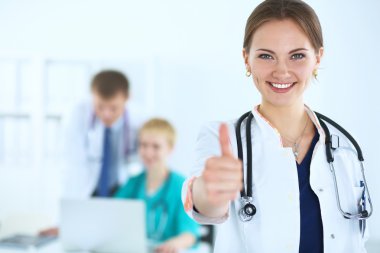 Female doctor shows a sign okay standing in hospital clipart