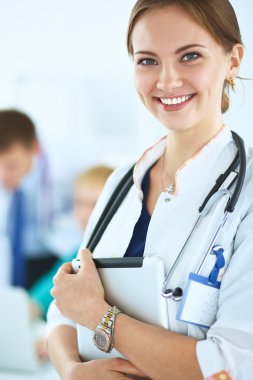 Tıbbî grubun önünde dosyası olan çekici bir kadın doktor.