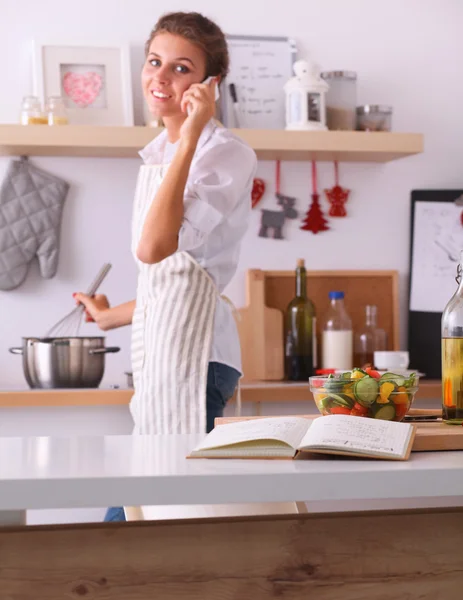 Portrait d'une femme souriante avec téléphone dans la cuisine à la maison — Photo