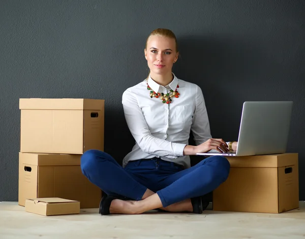 Mujer sentada en el suelo cerca de una caja con portátil —  Fotos de Stock