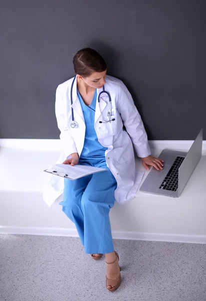 Nurse holding folder en het maken van aantekeningen - zitten op grijze achtergrond — Stockfoto