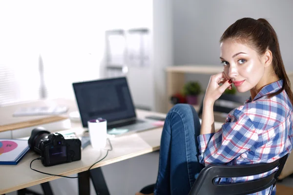 Female photographer sitting on the desk with laptop — Stock Photo, Image