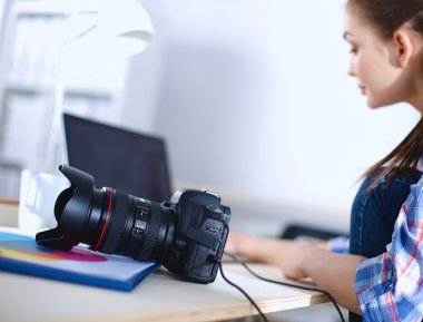 Female photographer sitting on the desk with laptop clipart