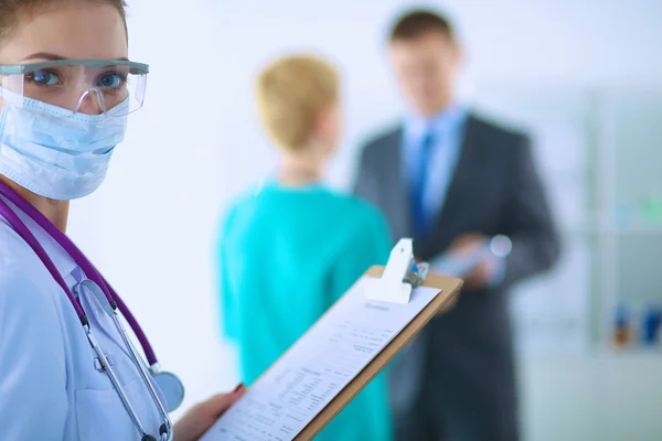 Woman doctor standing with folder at hospital — Stock Photo, Image