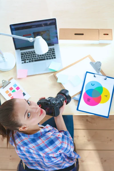 Vrouwelijke fotograaf zittend op het bureau met laptop — Stockfoto