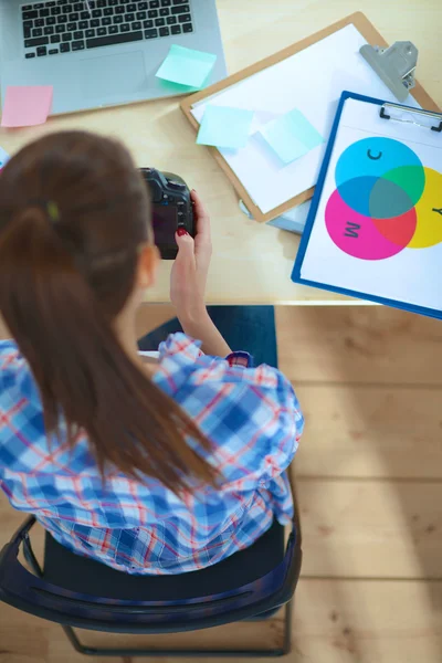 Vrouwelijke fotograaf zittend op het bureau met laptop — Stockfoto