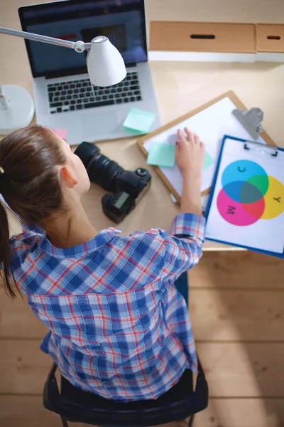 Vrouwelijke fotograaf zittend op het bureau met laptop — Stockfoto