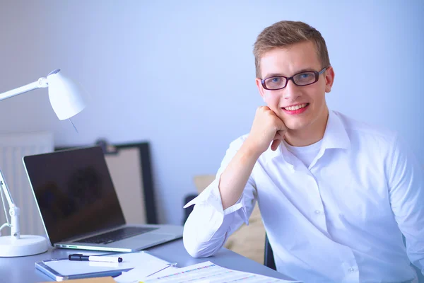 Молодой бизнесмен работает в офисе, сидит возле стола — стоковое фото