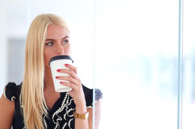 Ofiste kahve içen genç bir kadın.