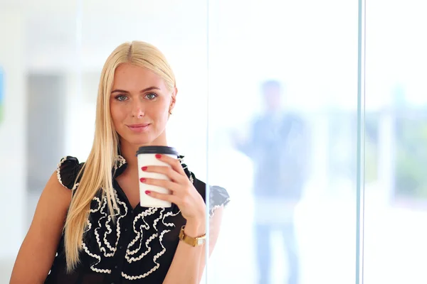 Een jonge vrouw die koffie drinkt op kantoor — Stockfoto