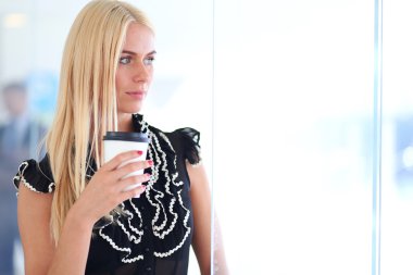 Ofiste kahve içen genç bir kadın.