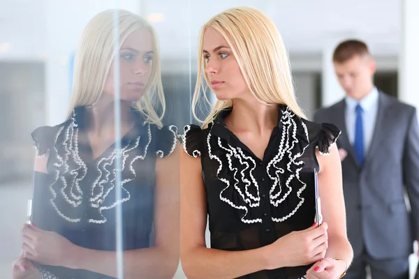 Zakenvrouw permanent op voorgrond met een tablet in haar handen — Stockfoto