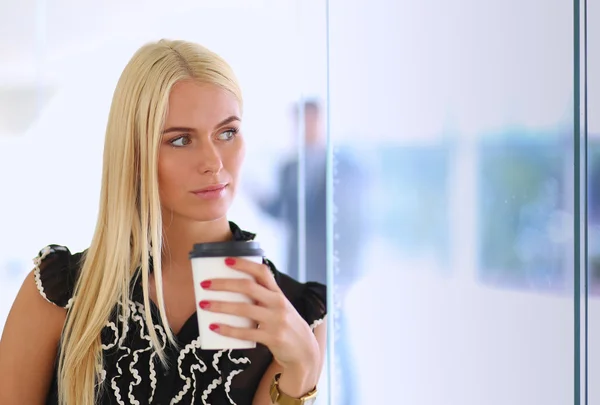 Empresaria sosteniendo una taza de café de pie en la oficina — Foto de Stock