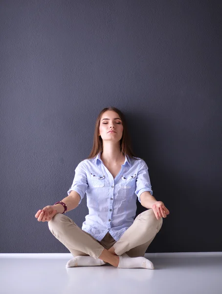 Jeune femme assise sur le sol près du mur sombre — Photo