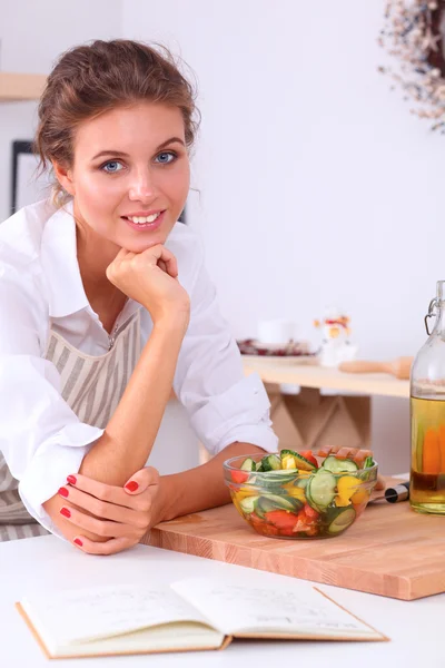 Sorrindo jovem mulher preparando salada na cozinha — Fotografia de Stock