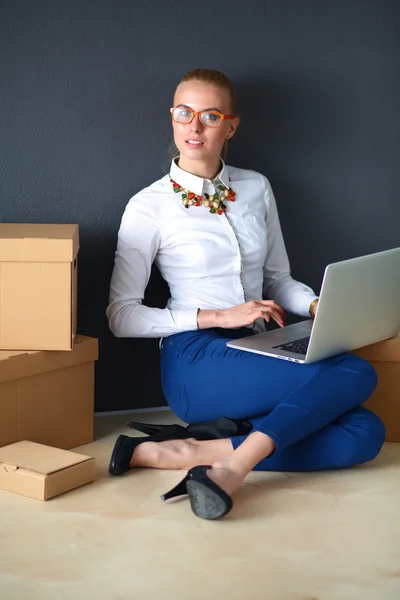 Woman sitting on the floor near a boxes  with laptop — Stock Photo, Image