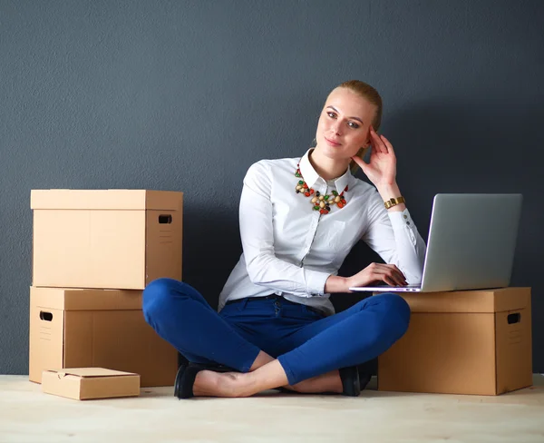 Frau sitzt auf dem Boden neben einer Schachtel mit Laptop — Stockfoto