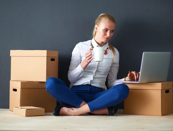 Woman sitting on the floor near a boxes  with laptop — Stock Photo, Image